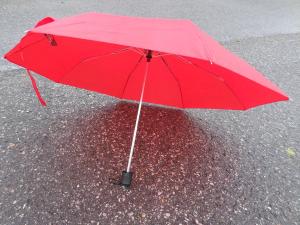 A red umbrella sitting on wet pavement