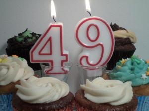 Candles in the shape of the numbers 4 and 9, surrounded by pretty cupcakes
