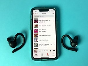 A mobile device showing different playlists and the author's ear buds.