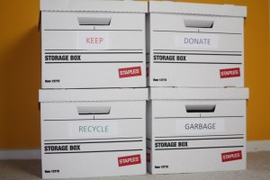 four banker's boxes intended to sort belongings. Their labels say keep, donate, recycle and garbage