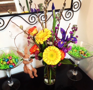 Easter flowers and treats on a black table.