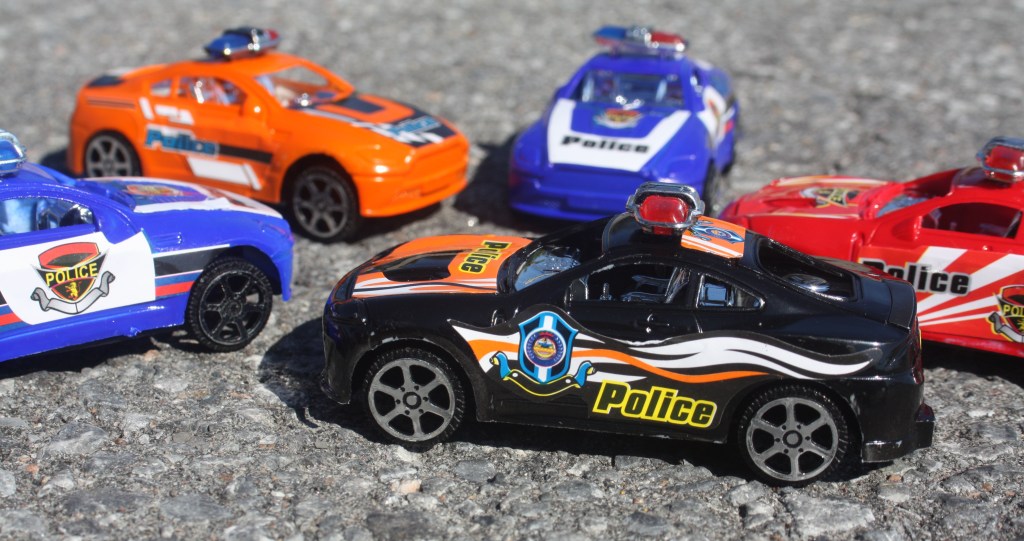 Five toy police cars on the pavement