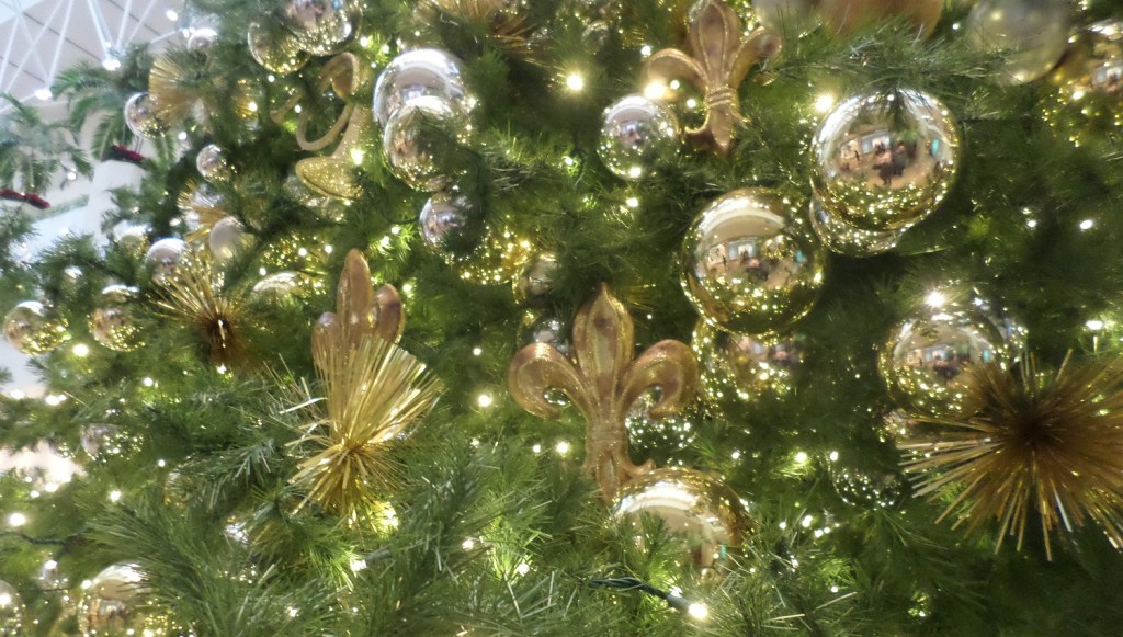 A close up of a green Christmas tree with beautiful gold ornaments.
