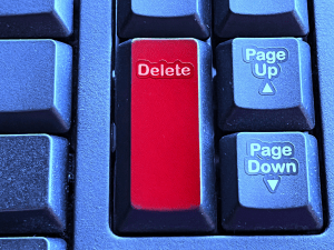 A close up of a computer keyboard with a red delete key.