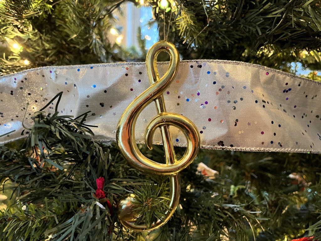 A close up shot of a treble clef ornament on a Christmas tree