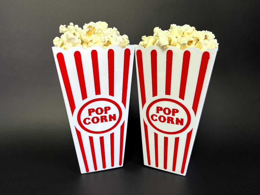 Two containers of popcorn on a black background