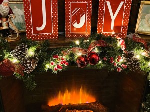 A fireplace decorated for Christmas with the letters spelling "joy" on the mantel.