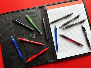 A variety of pens scattered on a portfolio.