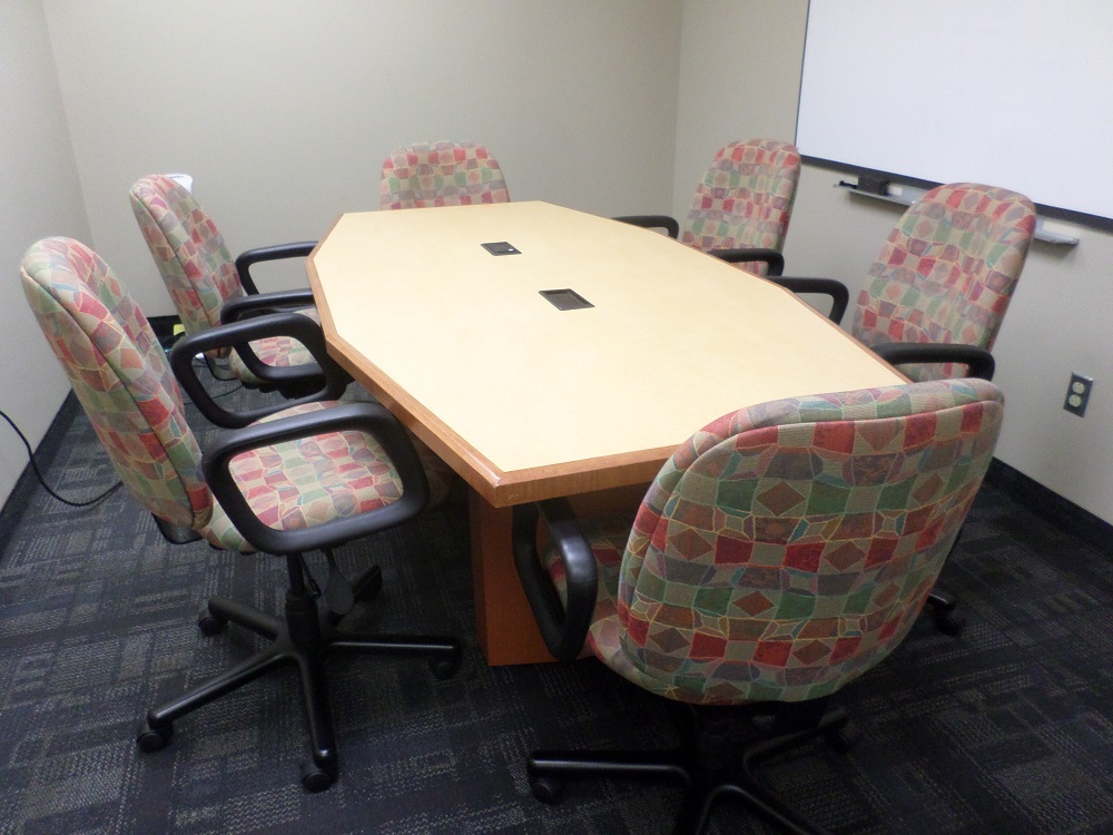 A small boardroom table for six, surrounded by chairs.