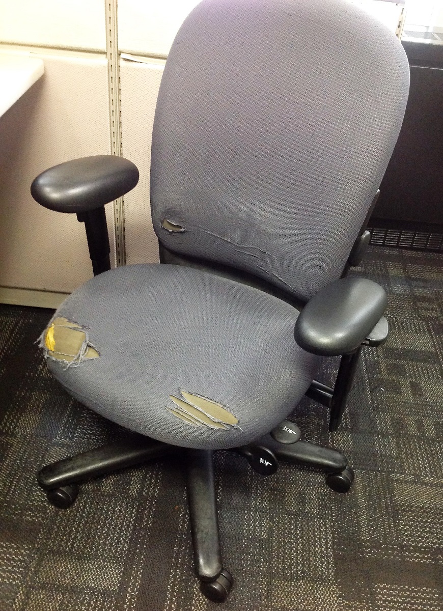 An office chair looking a little past its expiry date with its worn seat cushion and backrest