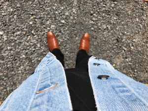 A photo taken by the author, looking down, in which he is wearing black jeans and a t-shirt, but a blue jean jacket and cognac chelsea boots.