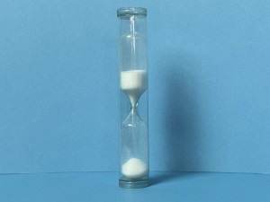 An hourglass with the white sand flowing through it, as time ticks away.