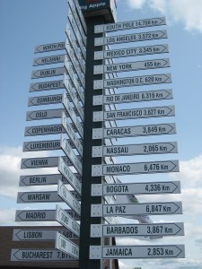 a sign post showing city names and the distances to travel to them