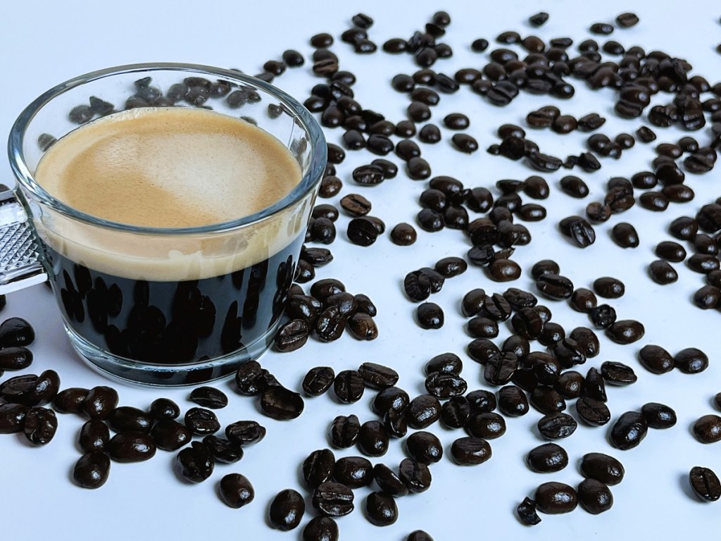 Coffee beans scattered by a cup of espresso.