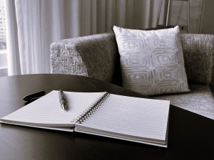 A pen sitting on an open journal in front of a chaise, ready for the author to write the next masterpiece.