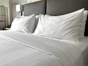 A simple but elegant and classic set of white sheets and pillowcases on a comfortable king sized bed.