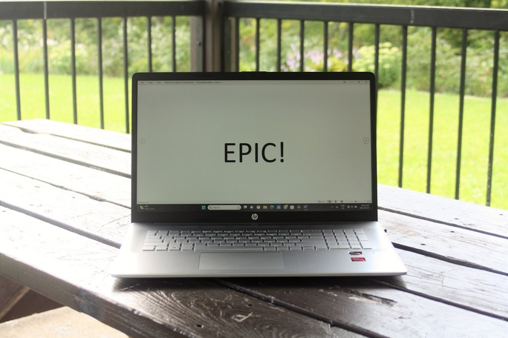 A notebook computer on a picnic table with the word "epic" appearing in large letters on the screen.