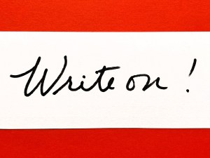 A white card on a red background, with the card showing "write on" in cursive.
