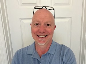 A photo of the author, smiling, with his glasses sitting on top of his head